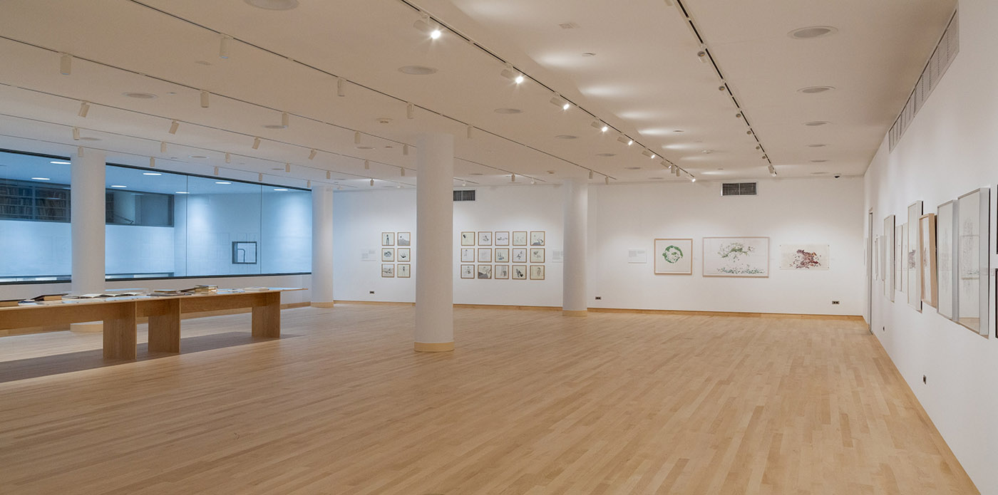 gallery space with white walls and wooden floor with a glass opening to the floor below