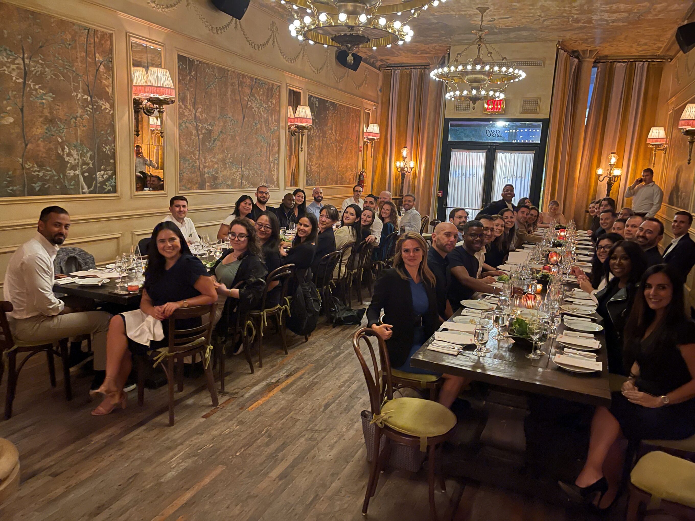 dbi team sitting at two large dinner tables at the hotel chelsea