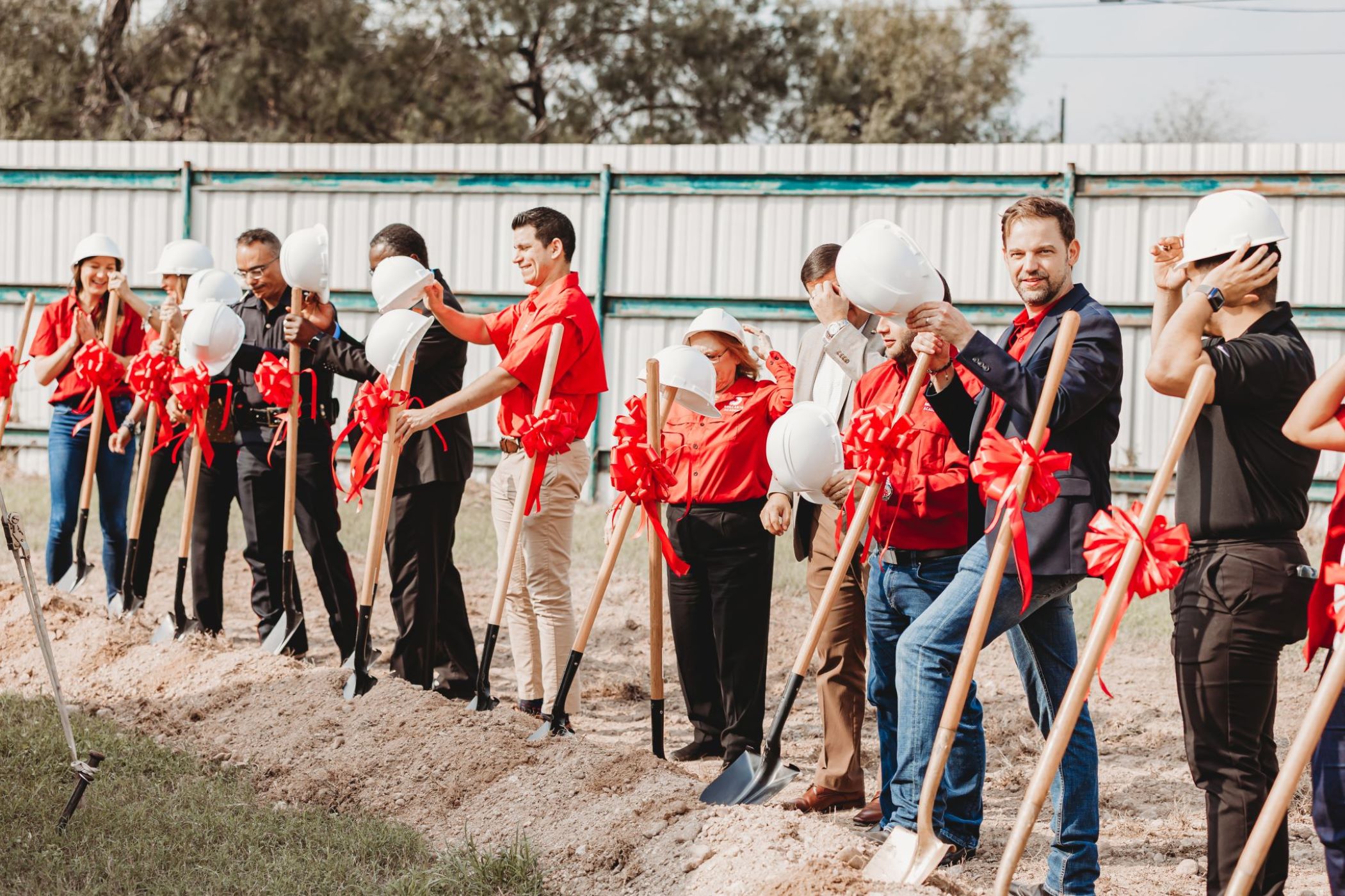 Group of people with shovels that have red bows tied onto them