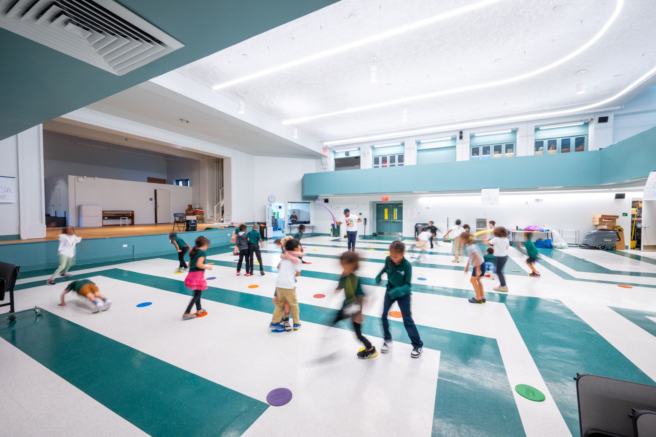 kids playing in a brightly lit gym with a patterned floor in blue and white