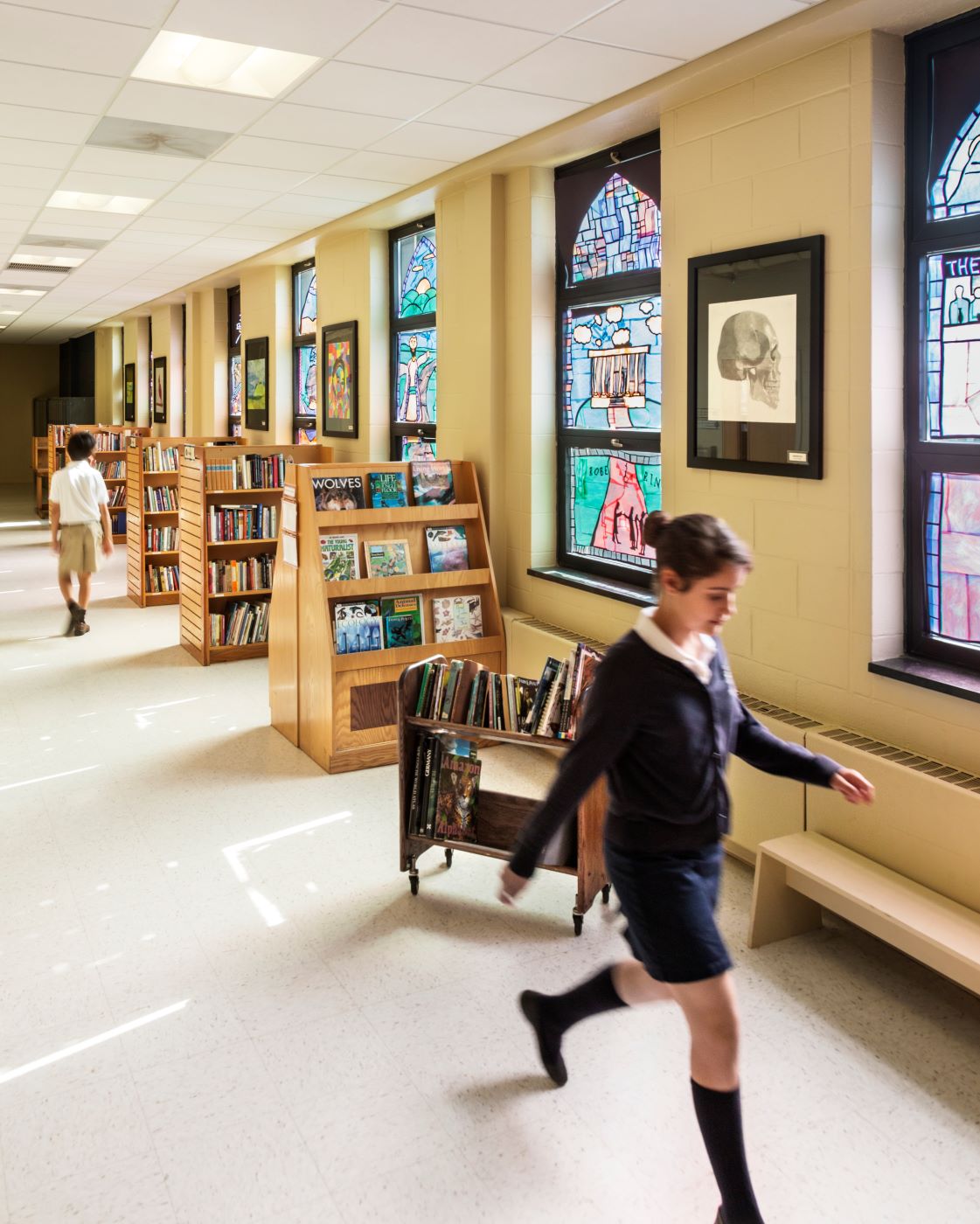 Internal school building with stained glass windows and a kid walking in the foreground