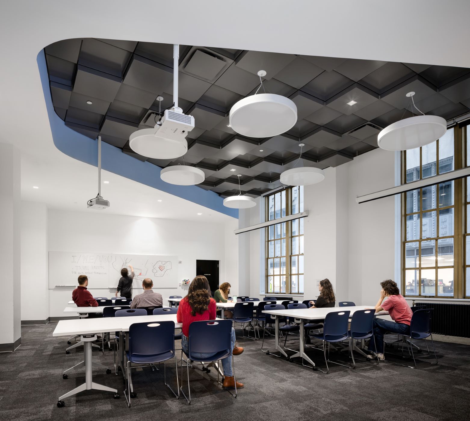 students studying in a white room with a cube style ceiling