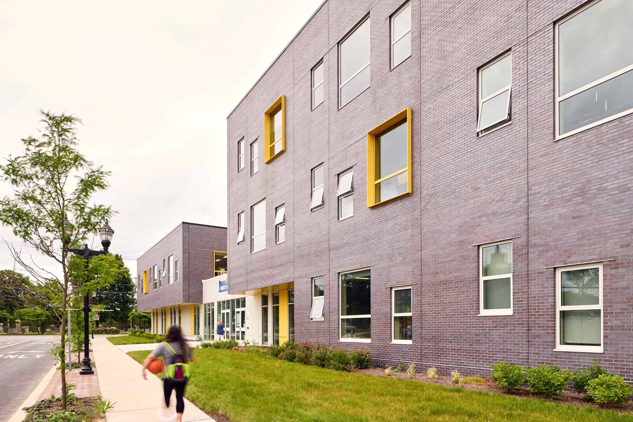 building with yellow windows and a kid walking on the sidewalk