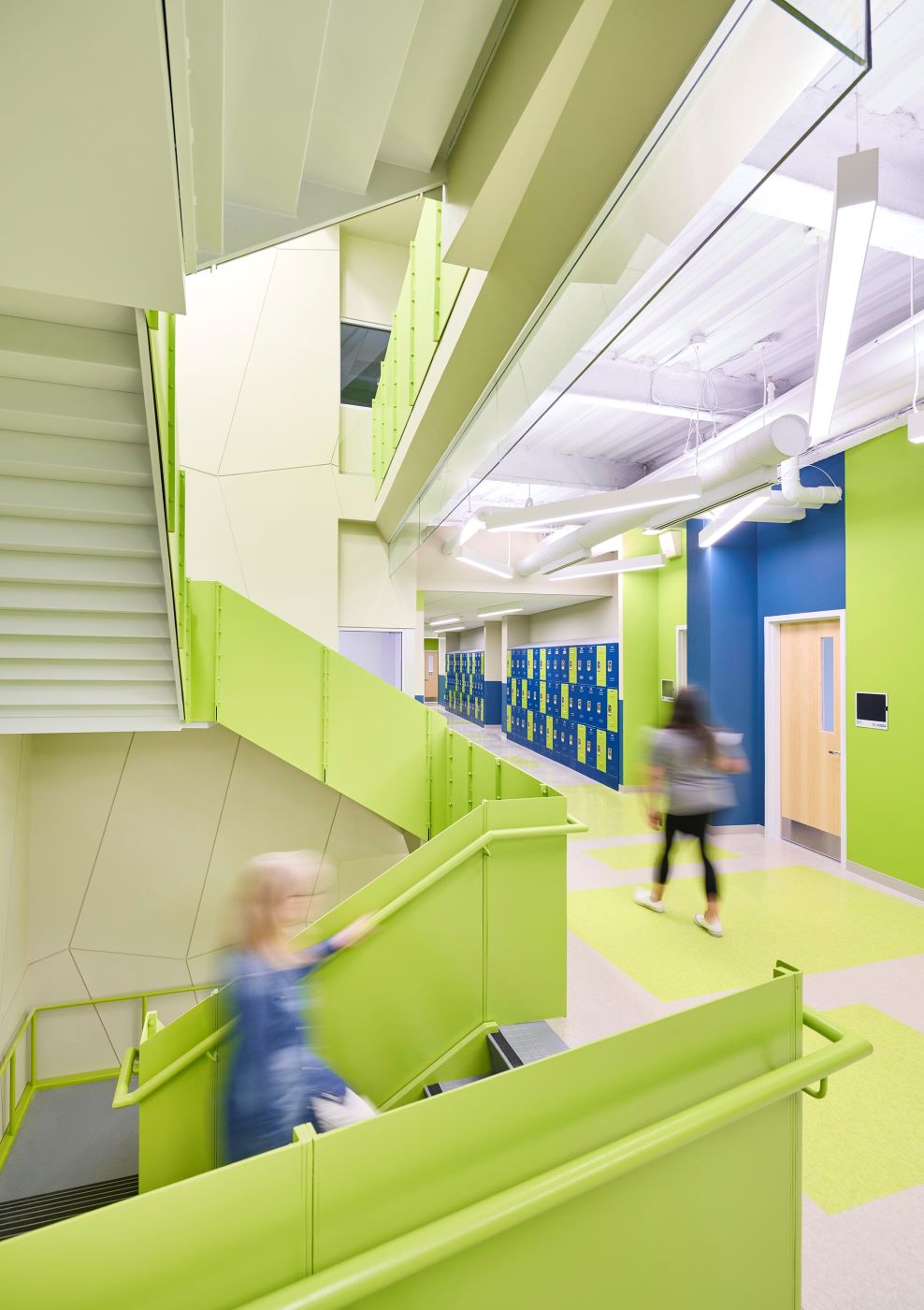 a green stairwell with people walking in it