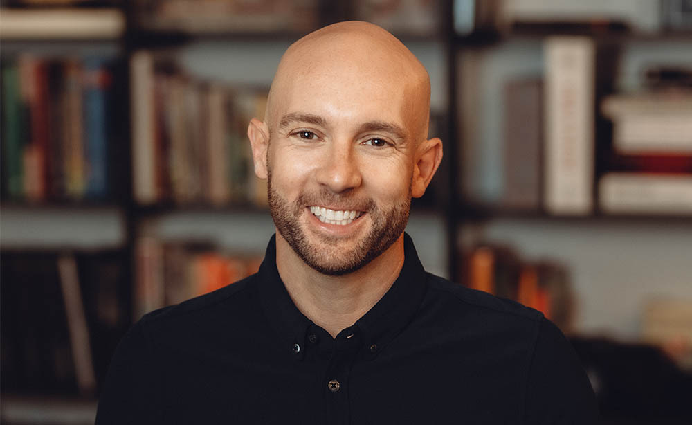 employee headshot in front of a blurry bookcase