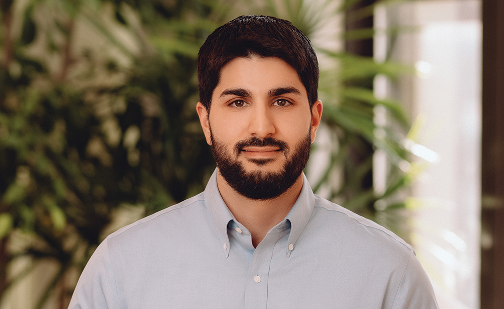 Man in blue button up shirt standing in a plant-filled office