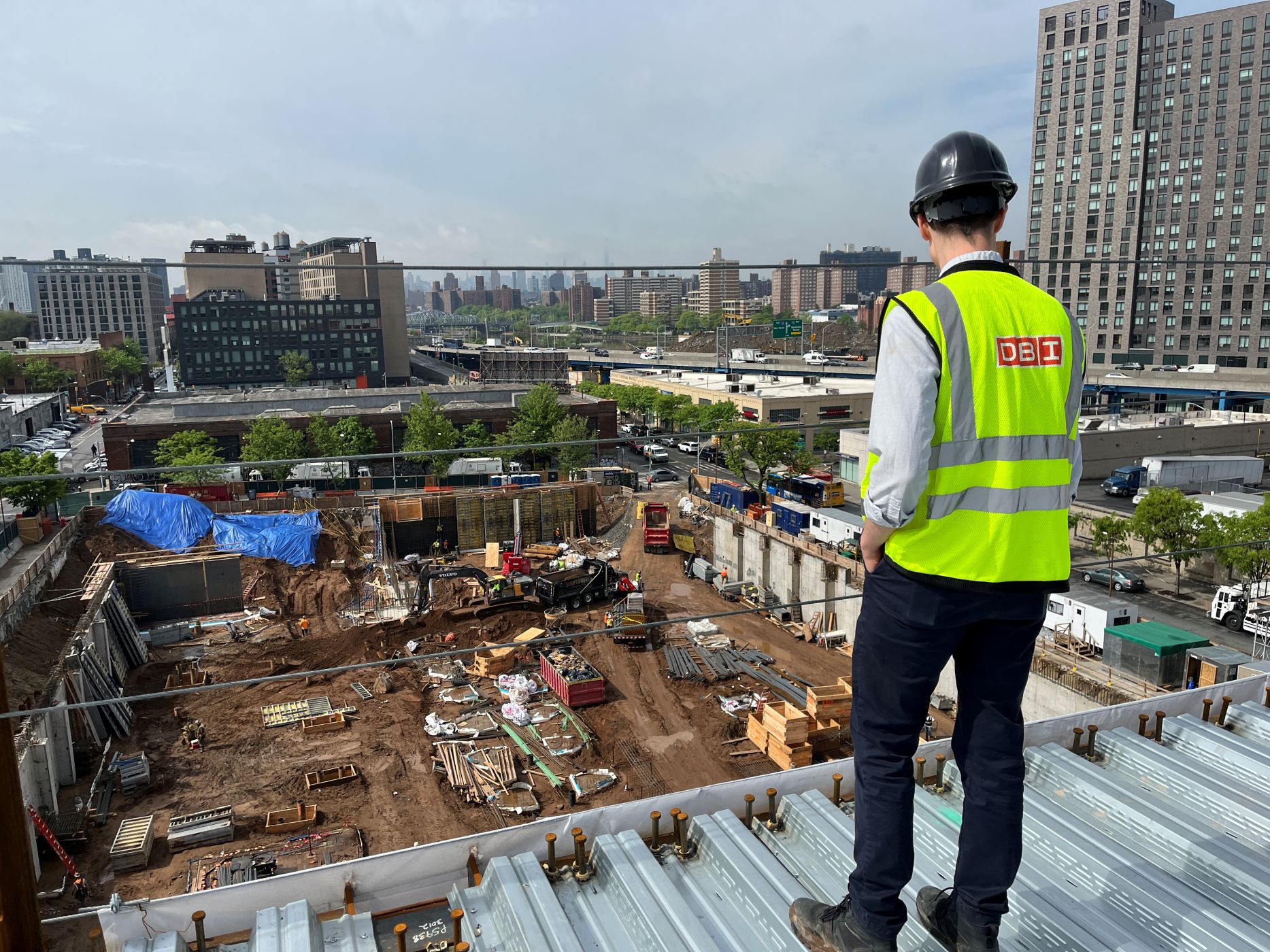 man in a yellow high visablity vest overlooking a large construction site