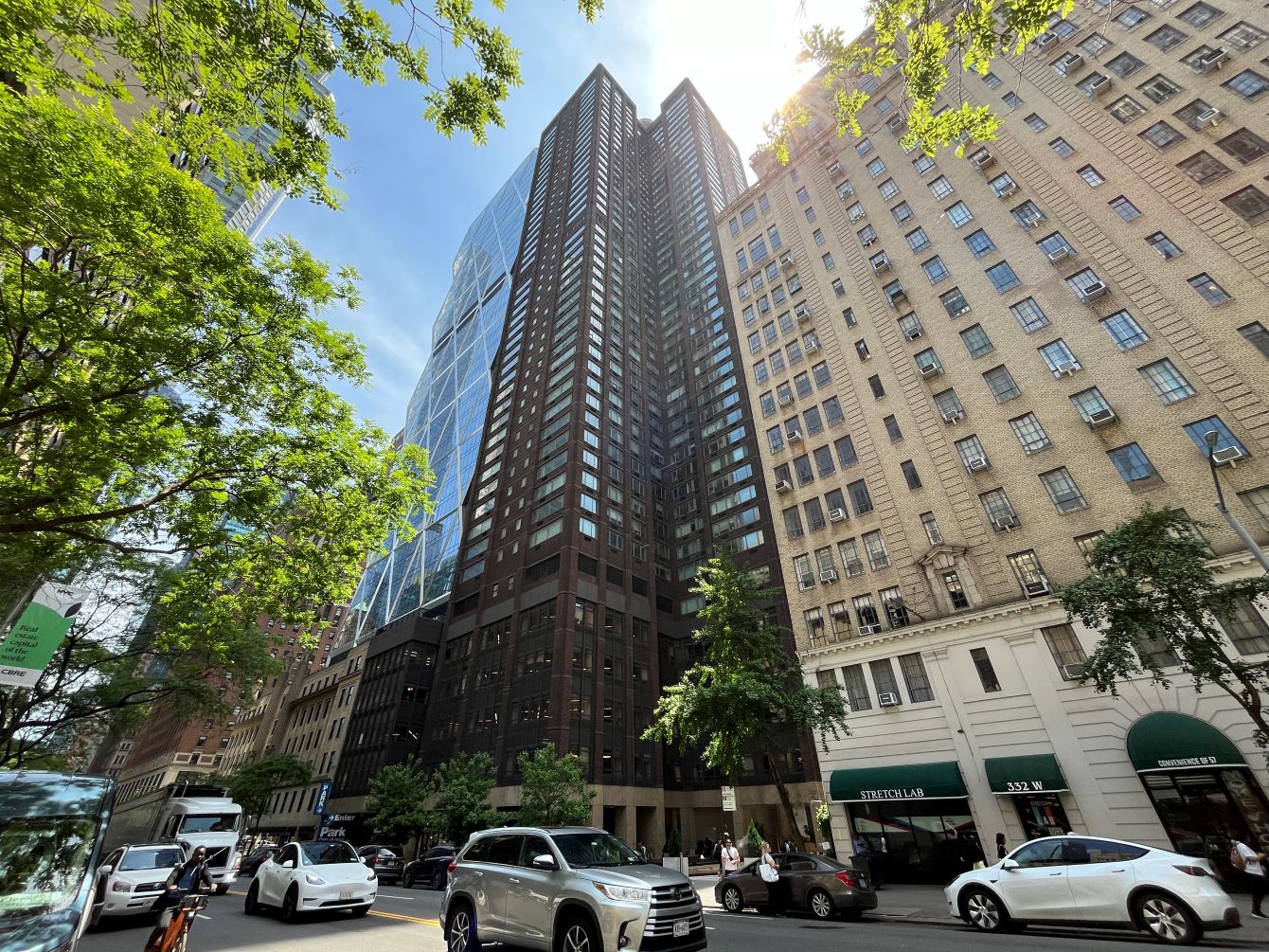 large tower in midtown manhattan, with blue sky and green trees