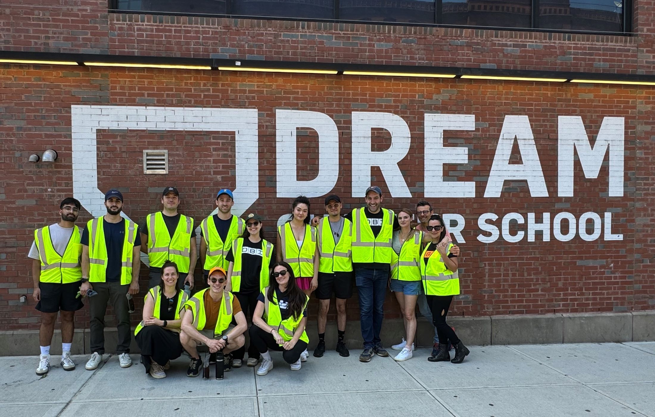 group of people in neon yellow vests in front of a large sign