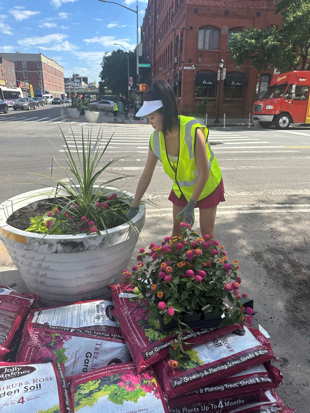 one person in neon yellow vests planting a tree into a large pot