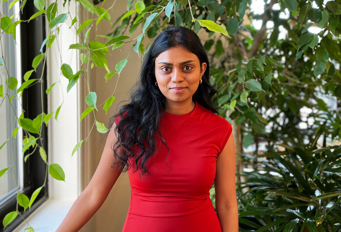 woman in red dress standing in front of trees