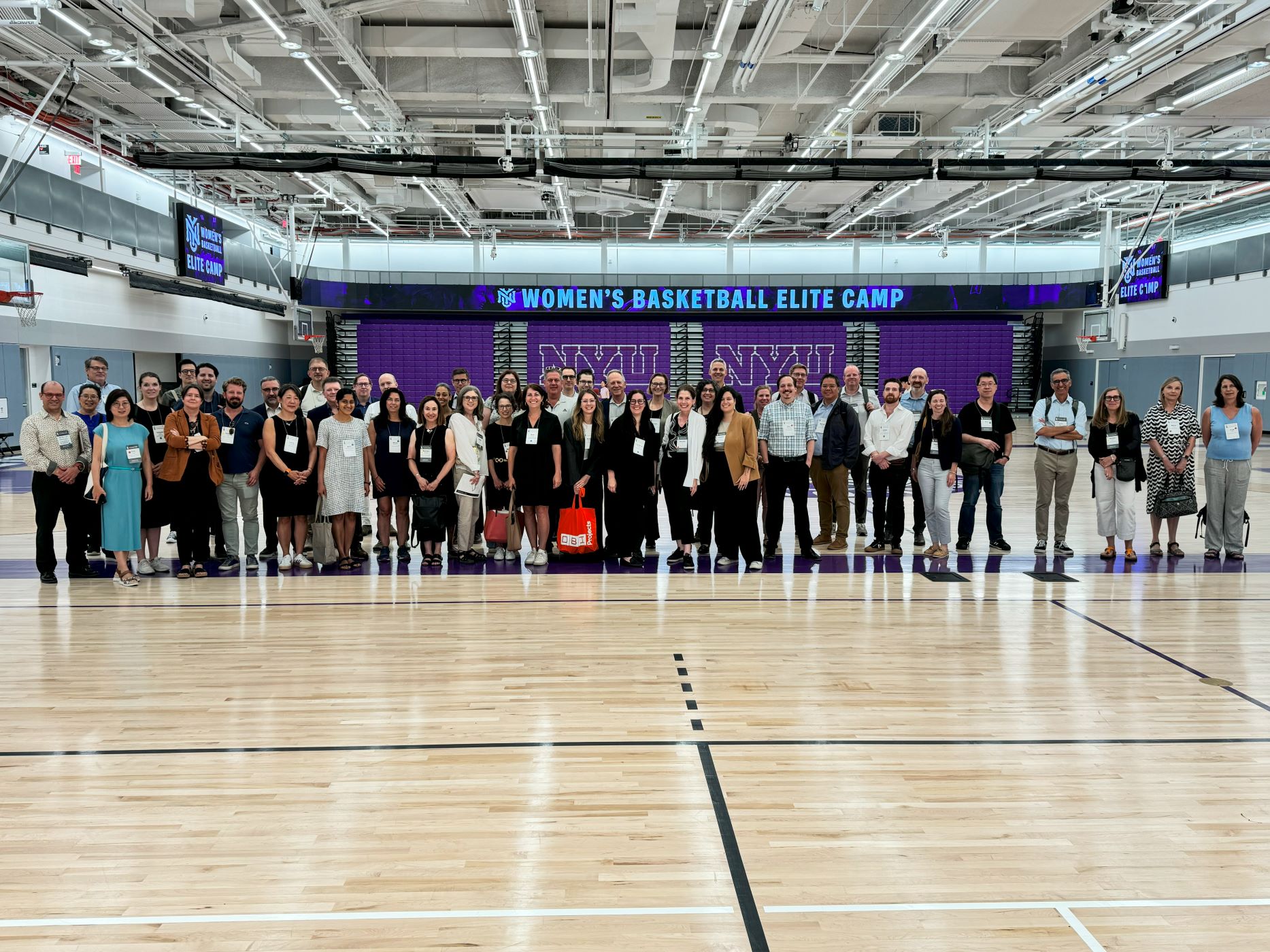 large group posing for a photo inside, standing on timber flooring