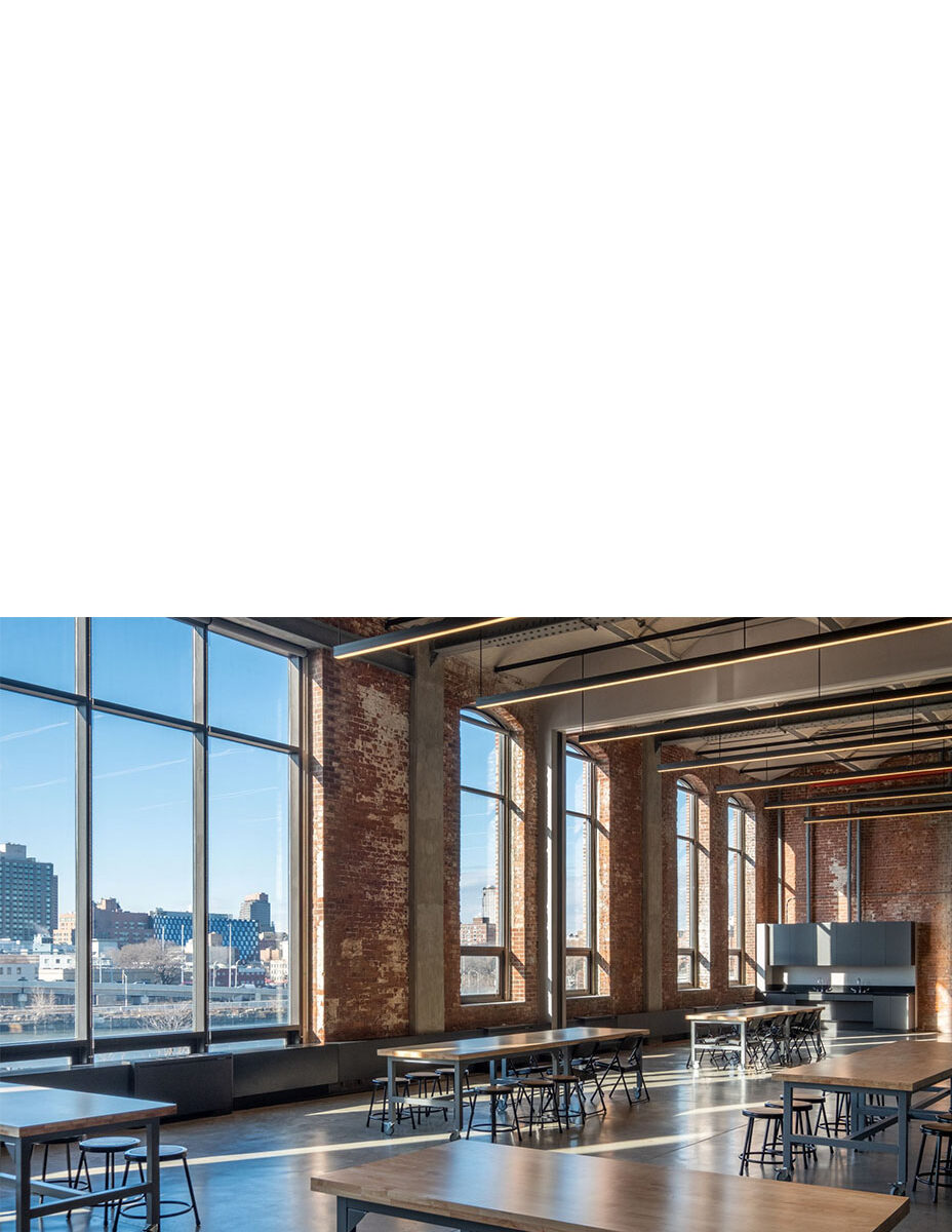 light-filled classroom with large windows and exposed brick walls