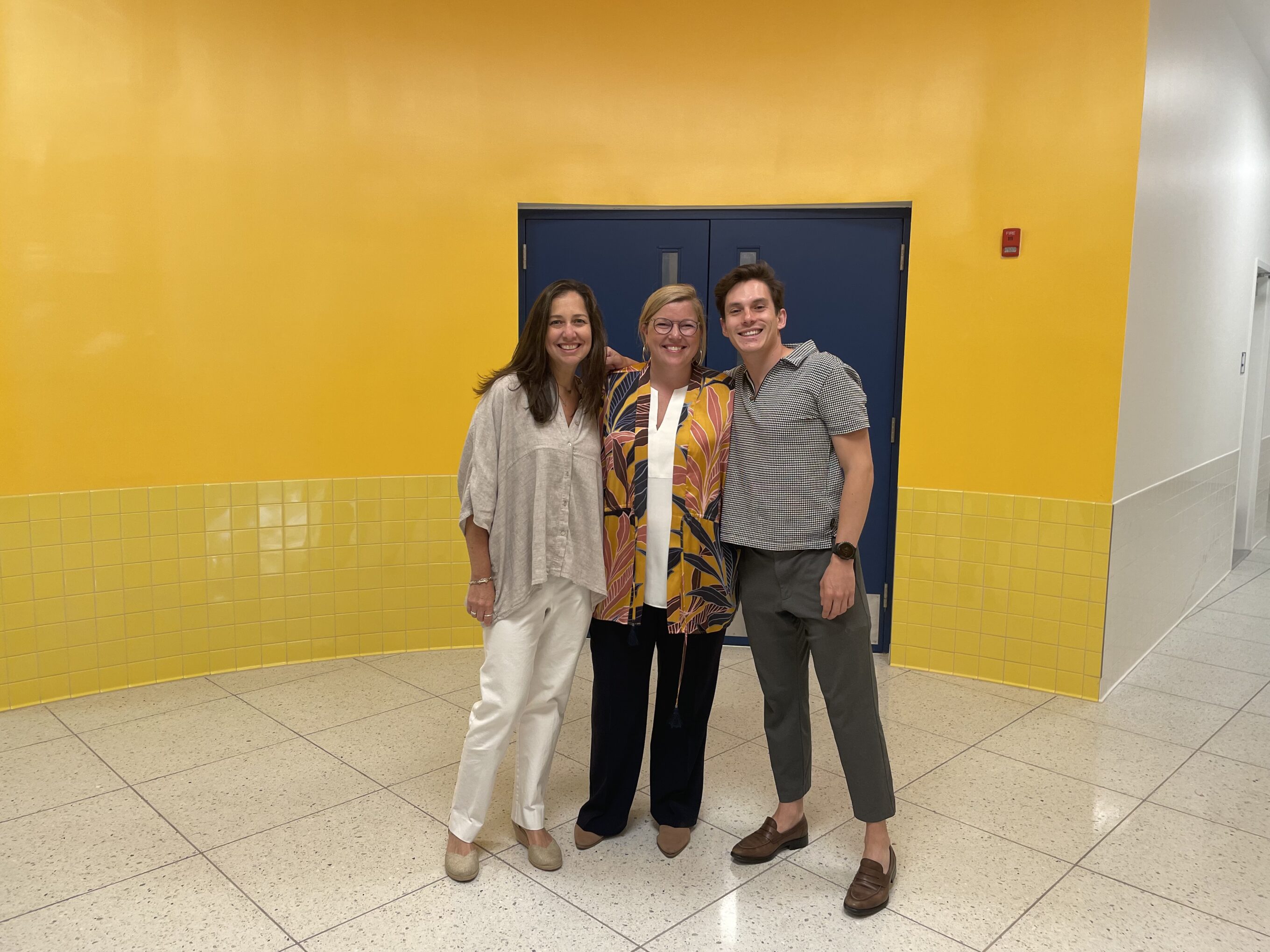 Three project team members stand together in the new building lobby