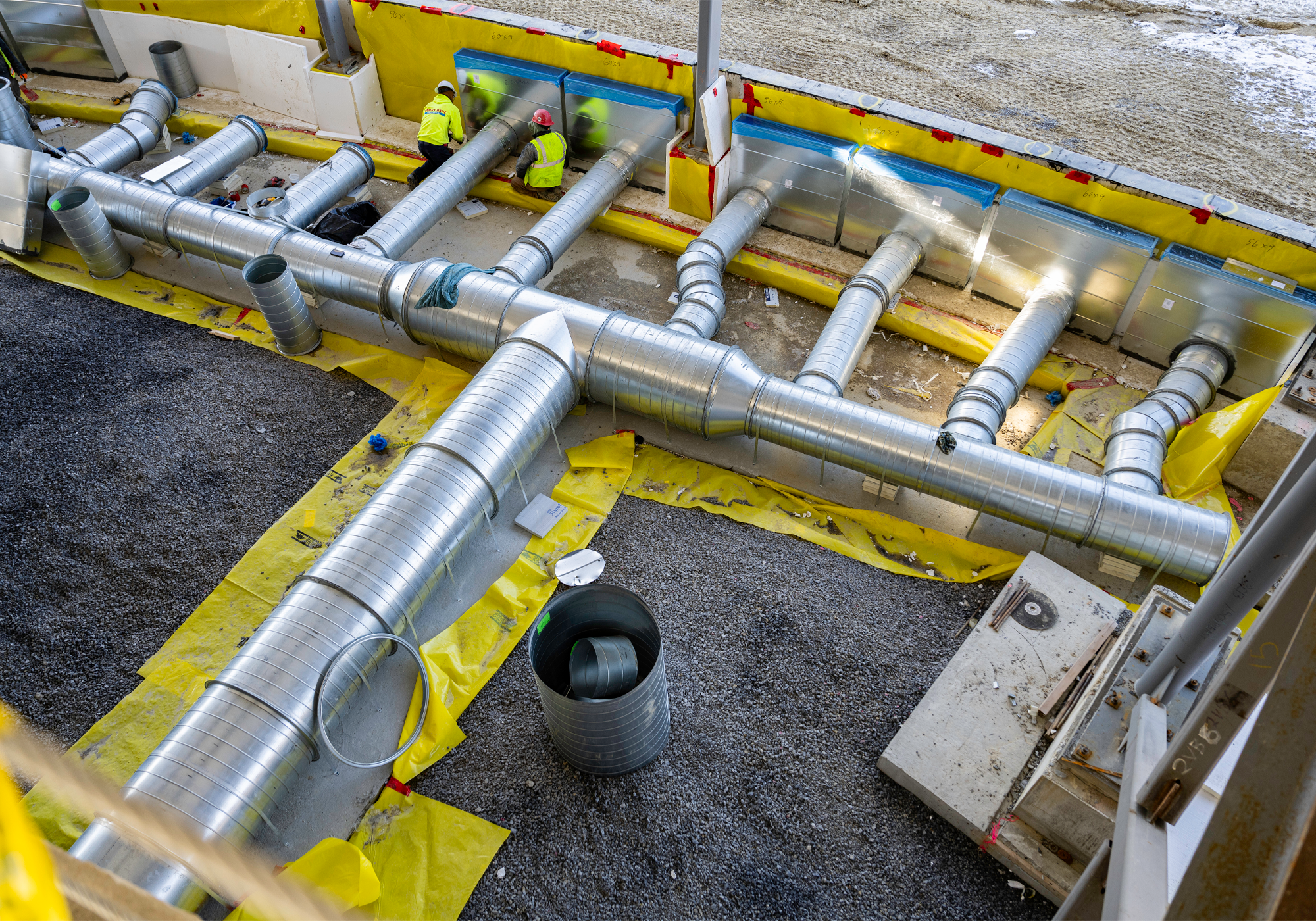 Set of HVAC tubes being installed by several construction workers