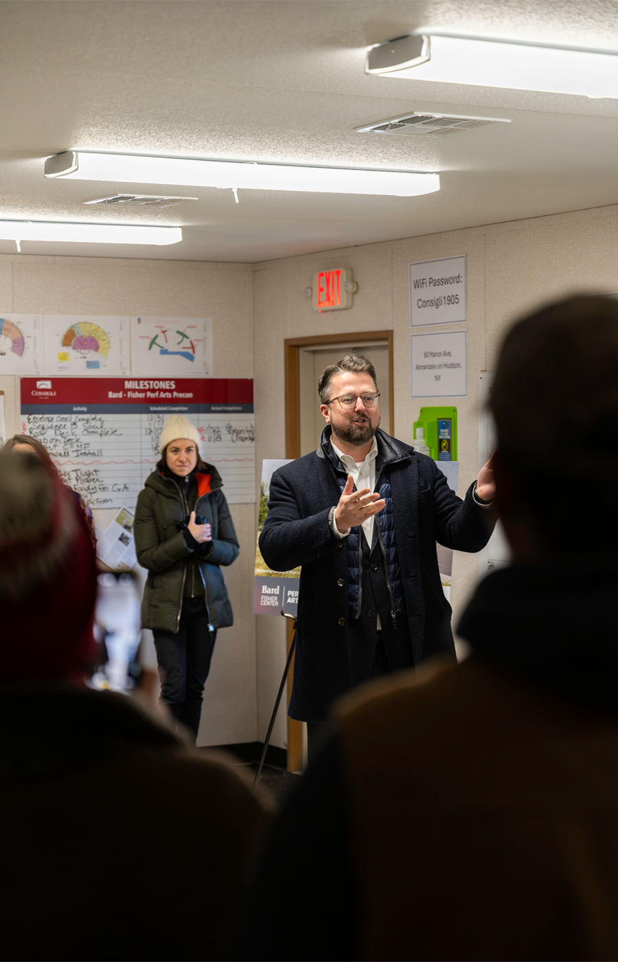 photo of a man inside a room giving a speech to a crowd of people